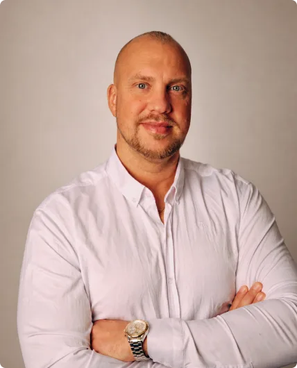 Mann med hvit skjorte og armkors, smilende portrett med klokke