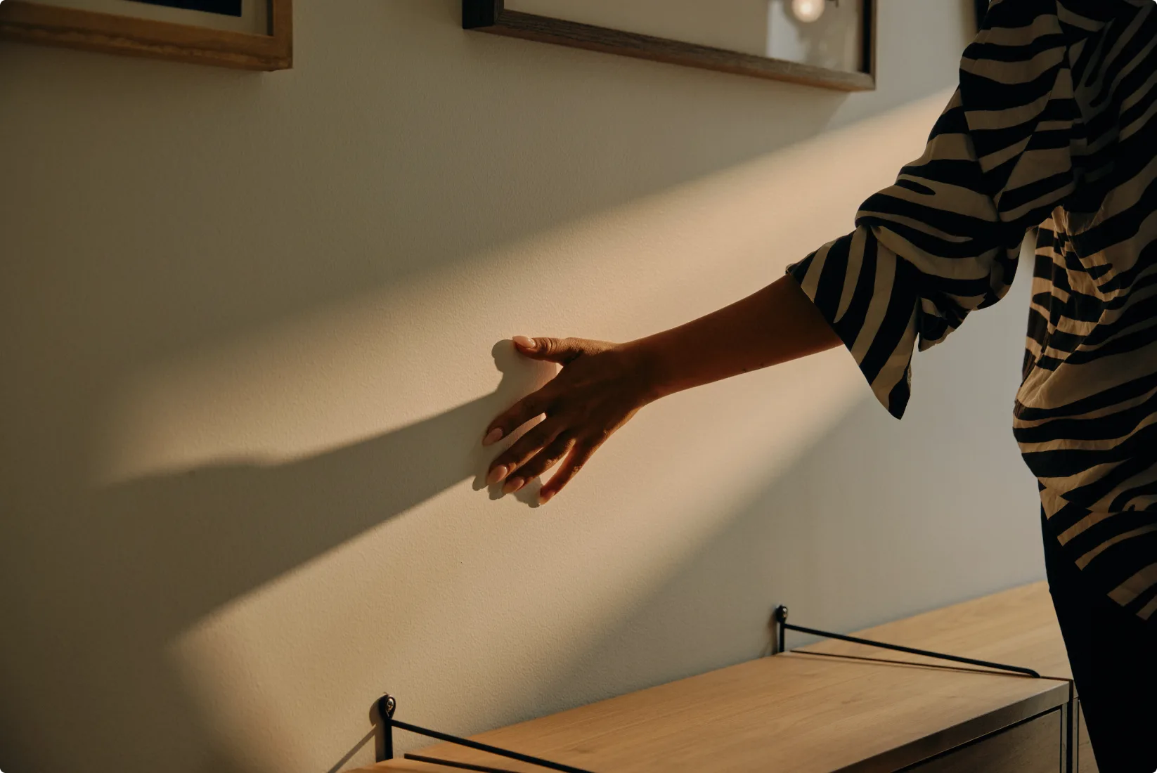 Person in striped shirt with hand extended over wooden surface